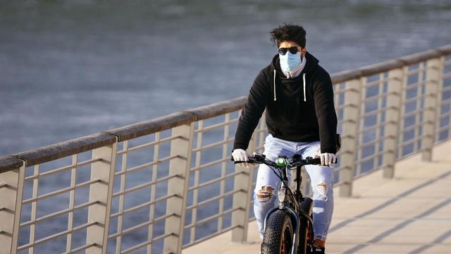 Ein Radfahrer mit Atemschutzmasker am Rheinboulevard in Köln.