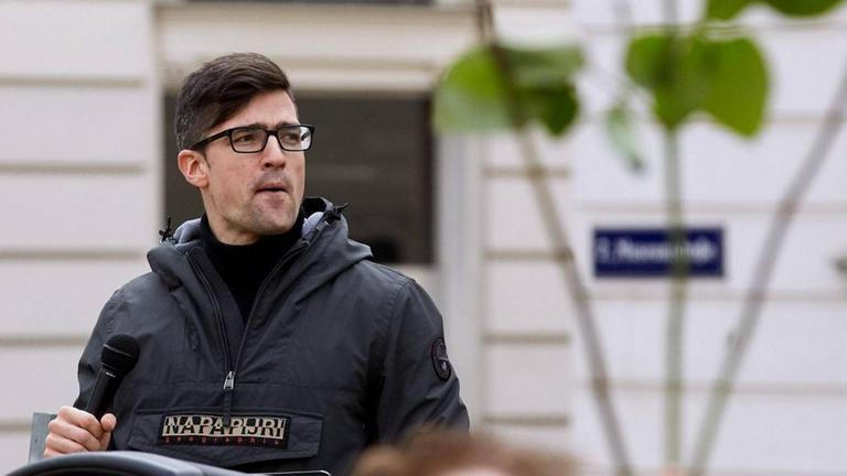 Martin Sellner steht vor Publikum und blickt argwöhnisch nach links. Martin Sellner steht vor Publikum und blickt argwöhnisch nach links.
