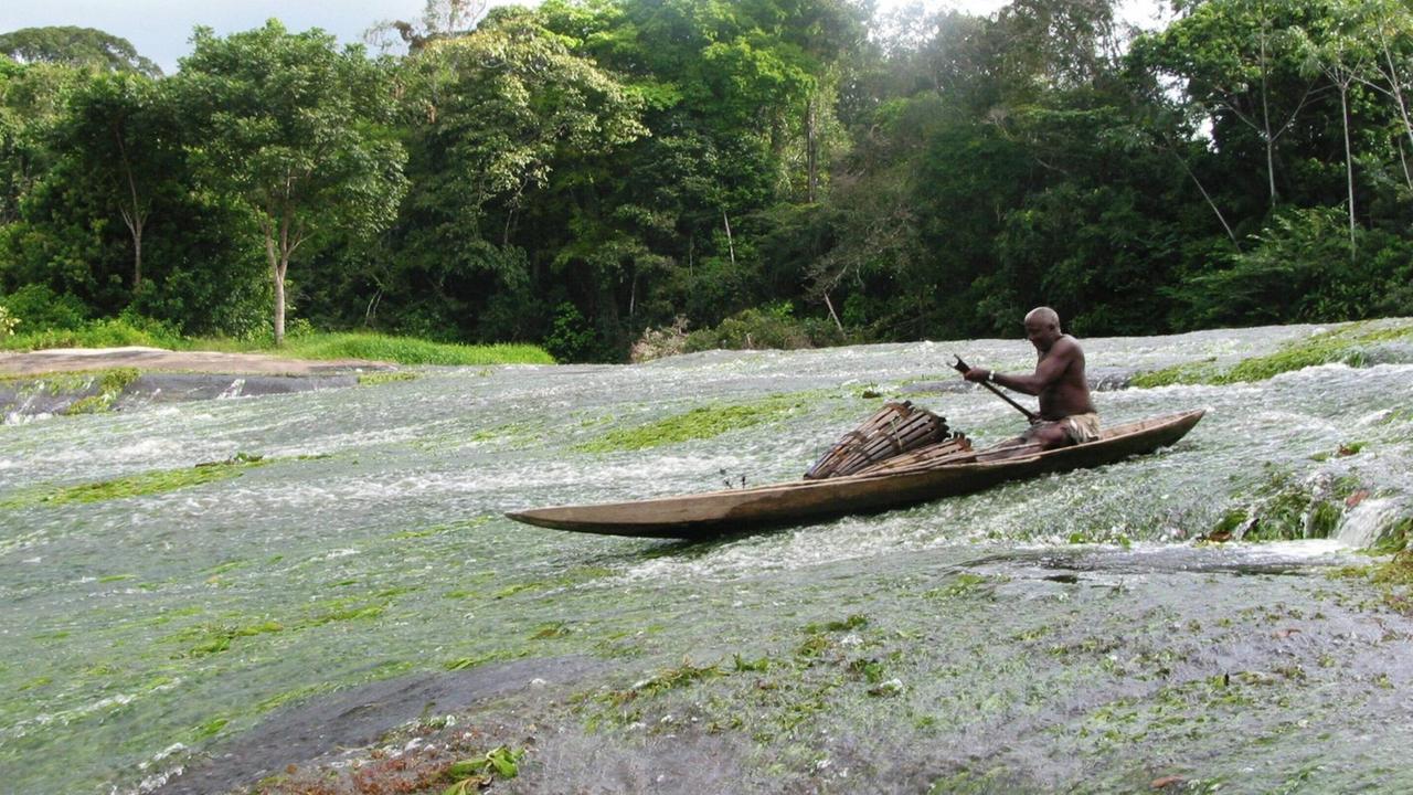 Mann aus Kajan in einem Einbaum manoevriert in einer Stromschnelle des Marowijne Flusses, Surinam Mann aus Kajan in einem Einbaum manoevriert in einer Stromschnelle des Marowijne Flusses, Surinam