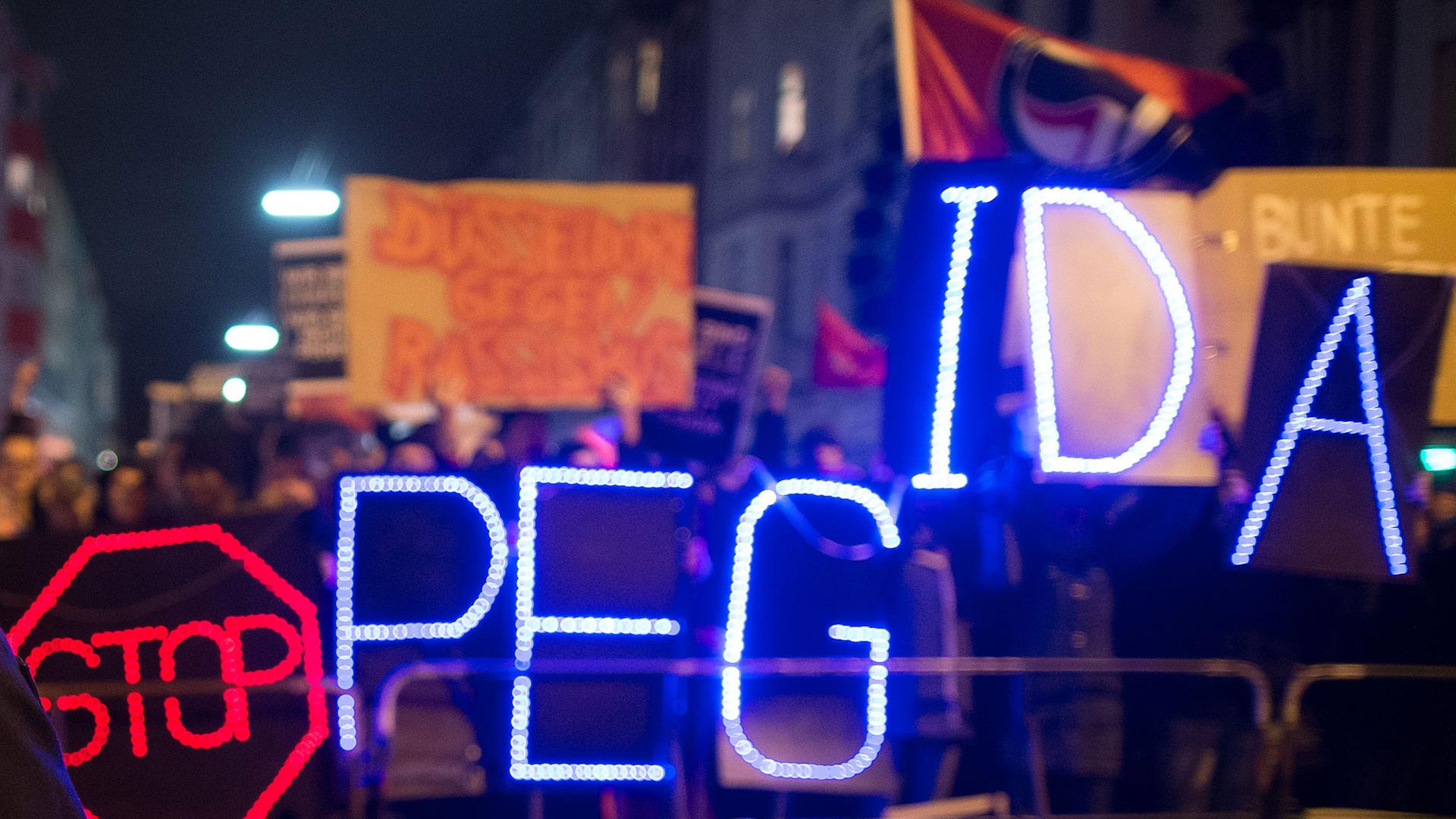 Gegner der Anti-Islam-Bewegung "Dügida" demonstrieren am 12.01.2015 in Düsseldorf (Nordrhein-Westfalen) mit einer Leuchtschrift "Stop PEGIDA" Gegner der Anti-Islam-Bewegung "Dügida" demonstrieren am 12.01.2015 in Düsseldorf (Nordrhein-Westfalen) mit einer Leuchtschrift "Stop PEGIDA"