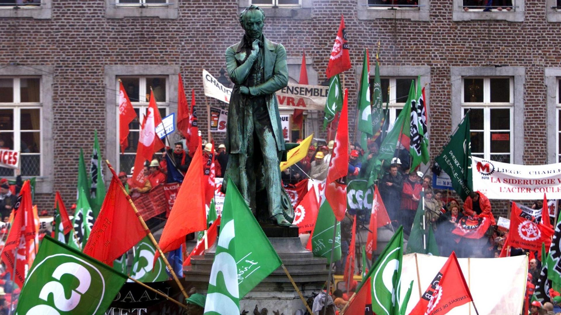 Auch heute noch trägt das Stahlwerk seinen Namen: Arbeiter von Cockerill-Seraing demonstrieren 2003 vor einer Statue von John Cockerill gegen die gefürchtete Übernahme durch Arcelor. Auch heute noch trägt das Stahlwerk seinen Namen: Arbeiter von Cockerill-Seraing demonstrieren 2003 vor einer Statue von John Cockerill gegen die gefürchtete Übernahme durch Arcelor.