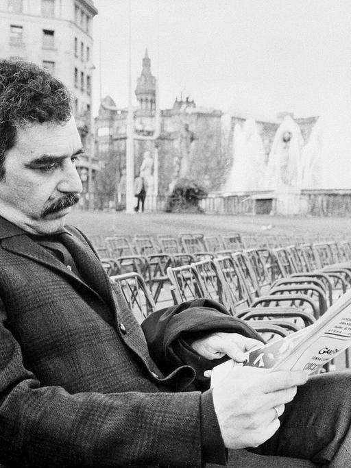 Der kolumbianische Schriftsteller Gabriel García Márquez sitzt mit einer Zeitung auf einer Parkbank.