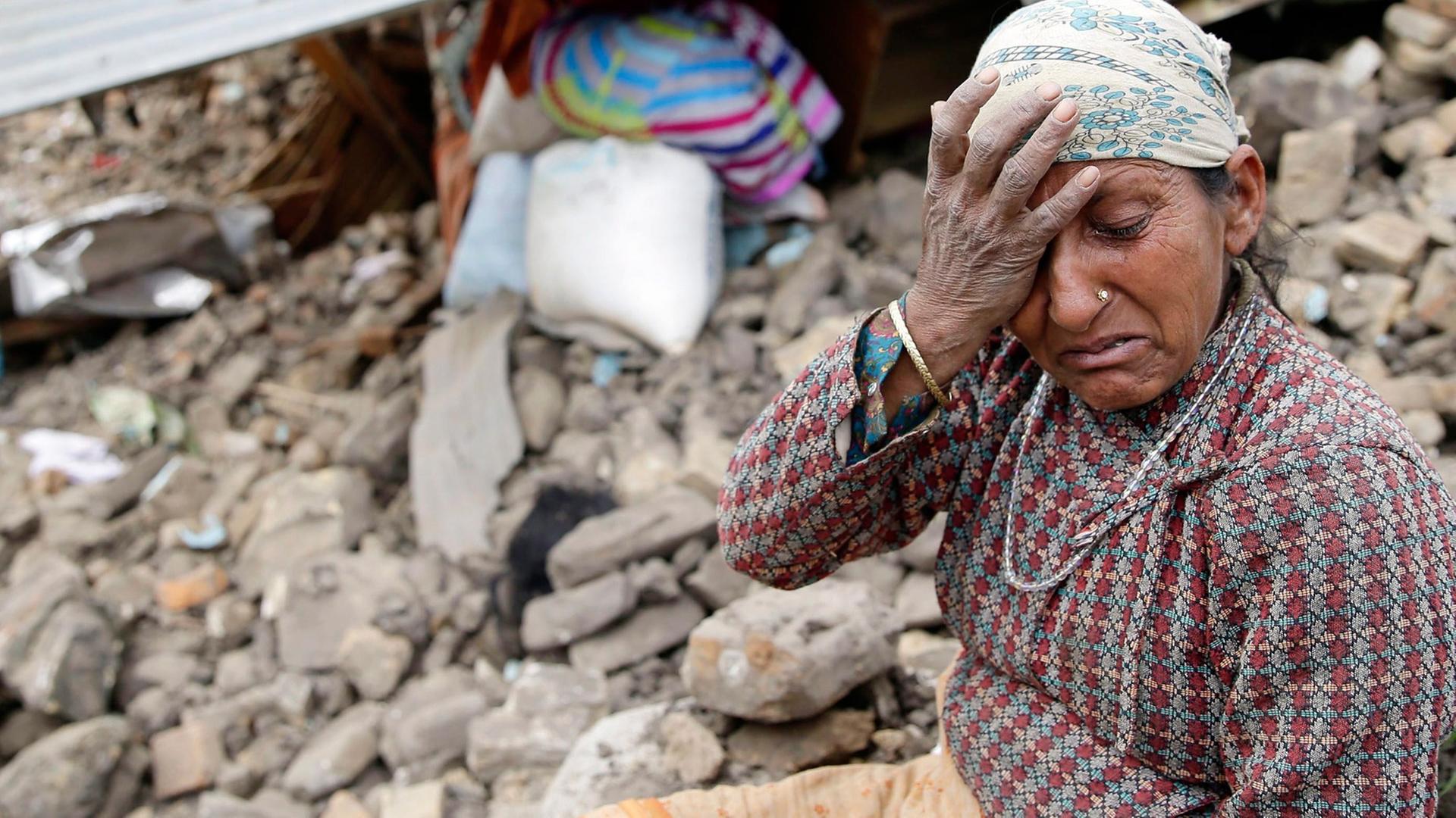 Eine Frau sitzt weinend vor ihrem zerstörten Haus in der nepalesischen Hauptstadt Kathmandu Eine Frau sitzt weinend vor ihrem zerstörten Haus in der nepalesischen Hauptstadt Kathmandu