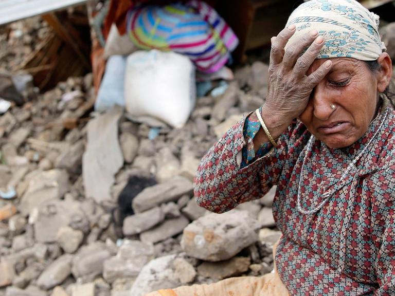 Eine Frau sitzt weinend vor ihrem zerstörten Haus in der nepalesischen Hauptstadt Kathmandu