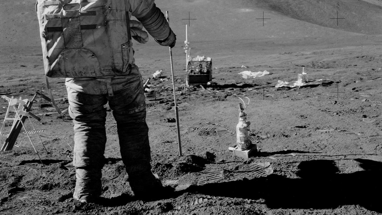 Astronaut Dave Scott hält auf dem Mond einen Bohrstab in der Hand. Astronaut Dave Scott hält auf dem Mond einen Bohrstab in der Hand.