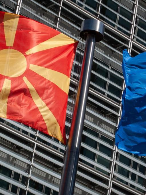 Eine Flagge von Nordmazedonien weht neben einer EU-Flagge im Wind vor dem Berlaymont-Gebäude der EU-Kommission