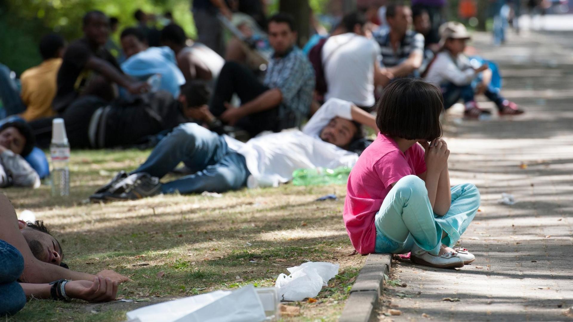 Ein Flüchtlingskind sitzt in Berlin auf dem Gelände des Landesamtes für Gesundheit und Soziales (LaGeSo) auf einem Bordstein. Ein Flüchtlingskind sitzt in Berlin auf dem Gelände des Landesamtes für Gesundheit und Soziales (LaGeSo) auf einem Bordstein.
