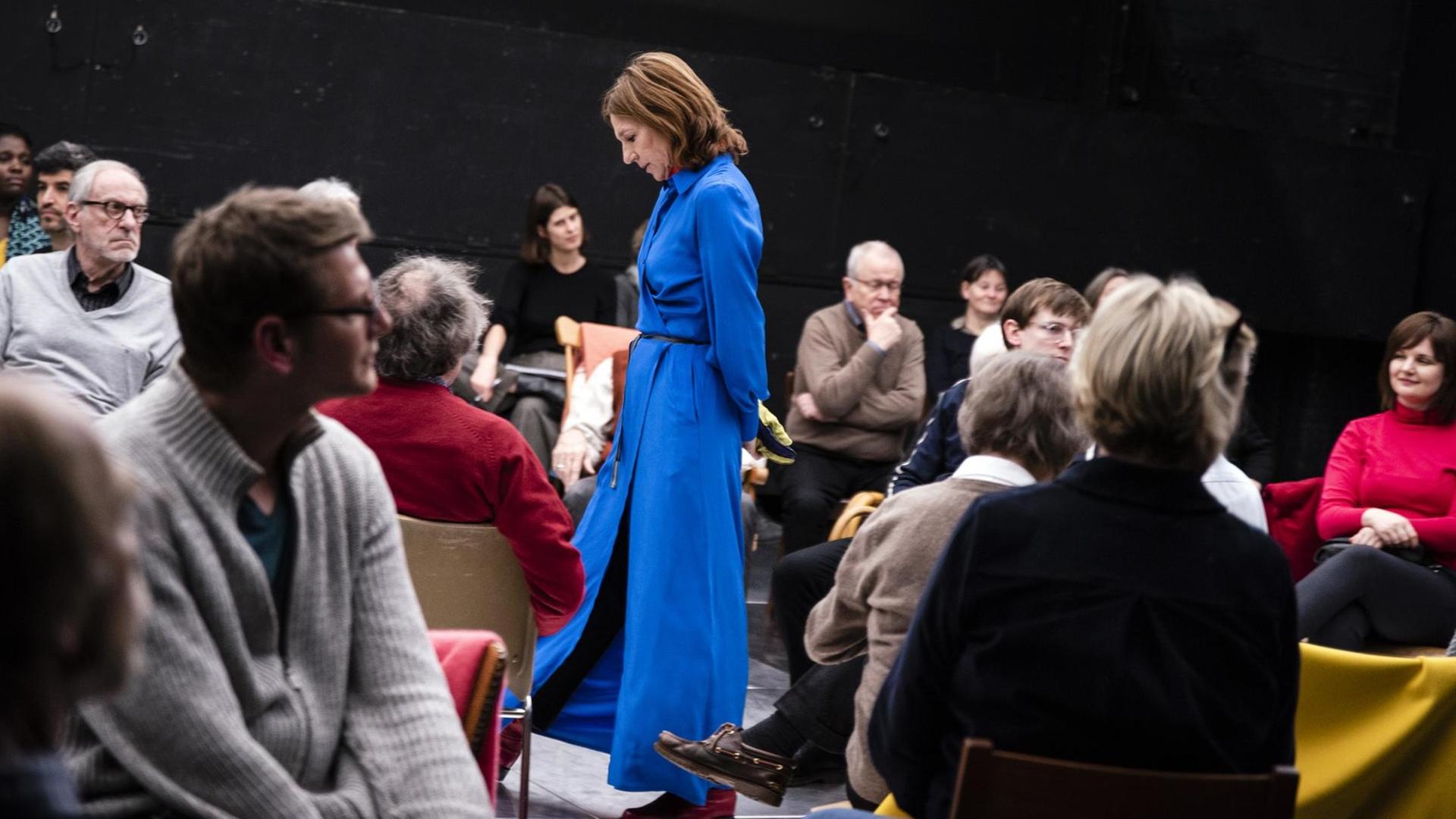 Die Schauspielerin Elsie de Brauw steht in einen langen blauen Mantel gekleidet in den Zuschauerreihen im Schauspielhaus Bochum. Ihr Kopf ist gesenkt. Die Schauspielerin Elsie de Brauw steht in einen langen blauen Mantel gekleidet in den Zuschauerreihen im Schauspielhaus Bochum. Ihr Kopf ist gesenkt.