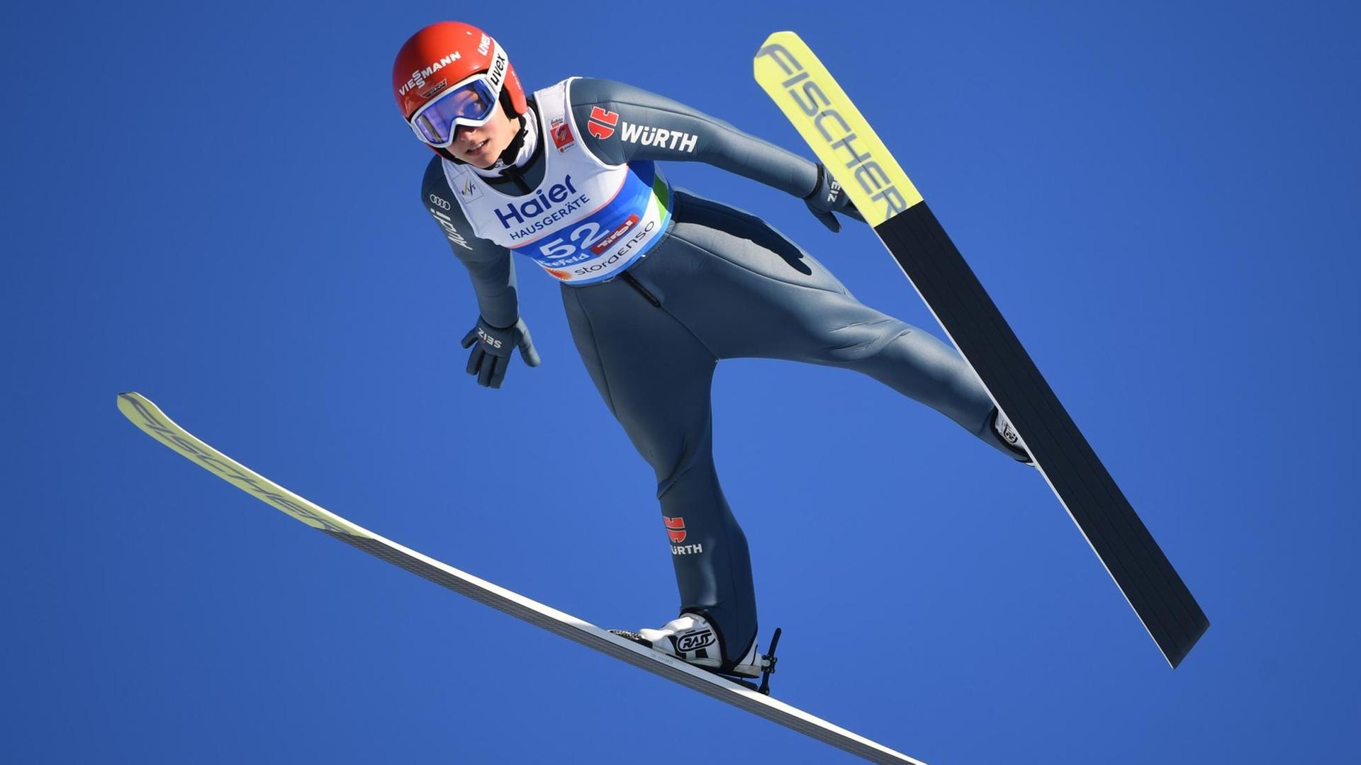 Das Bild zeigt Skispringen Katharina Althaus in der Luft vor einem blauen Himmel. Das Bild zeigt Skispringen Katharina Althaus in der Luft vor einem blauen Himmel.