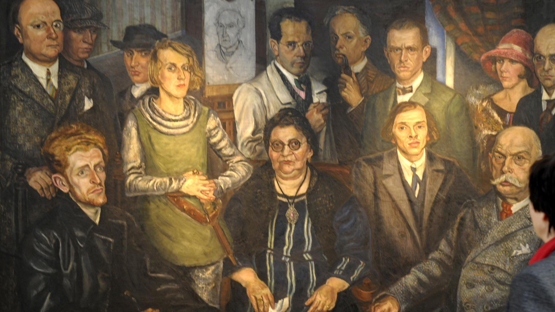 Das Gemälde von Arthur Kaufmann zeigt Johanna Ey, auch genannt "Mutter Ey", im Kreise der Künstergruppe "Das Junge Rheinland".