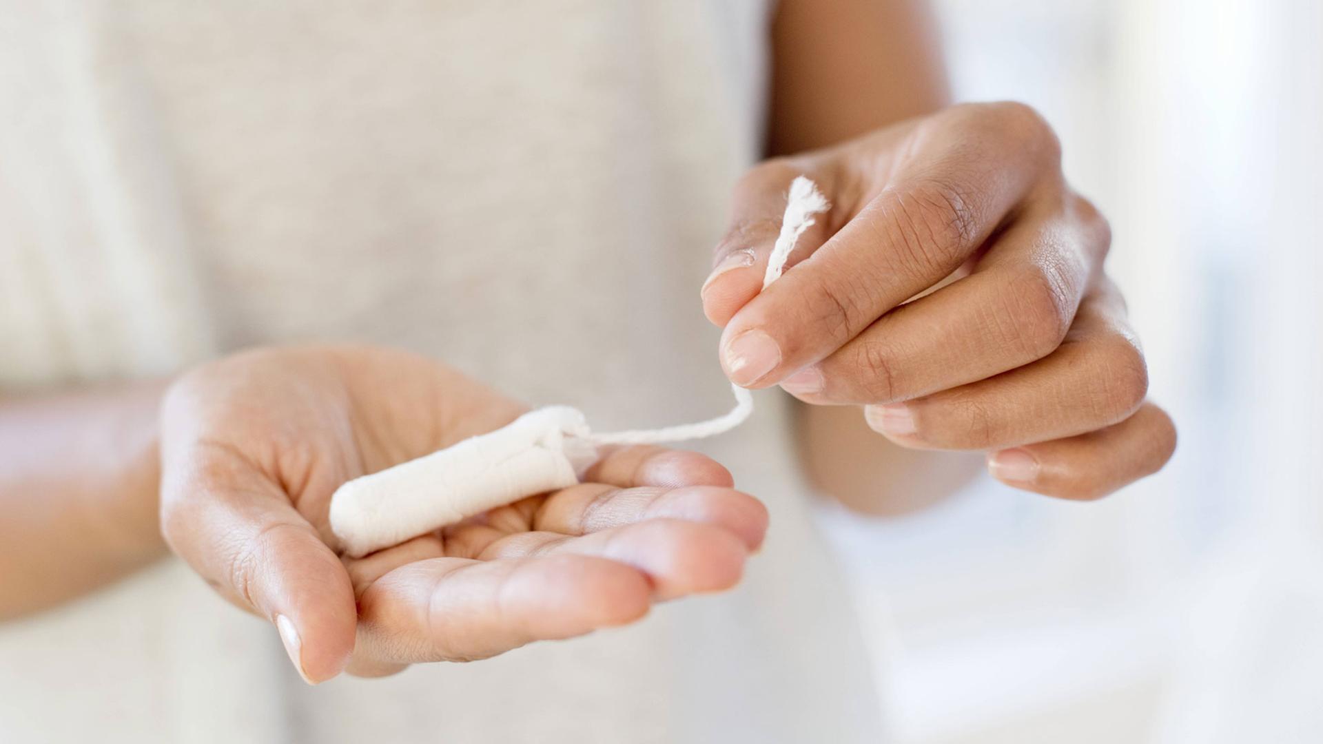 Eine Frau hält einen Tampon in der Hand. Eine Frau hält einen Tampon in der Hand.