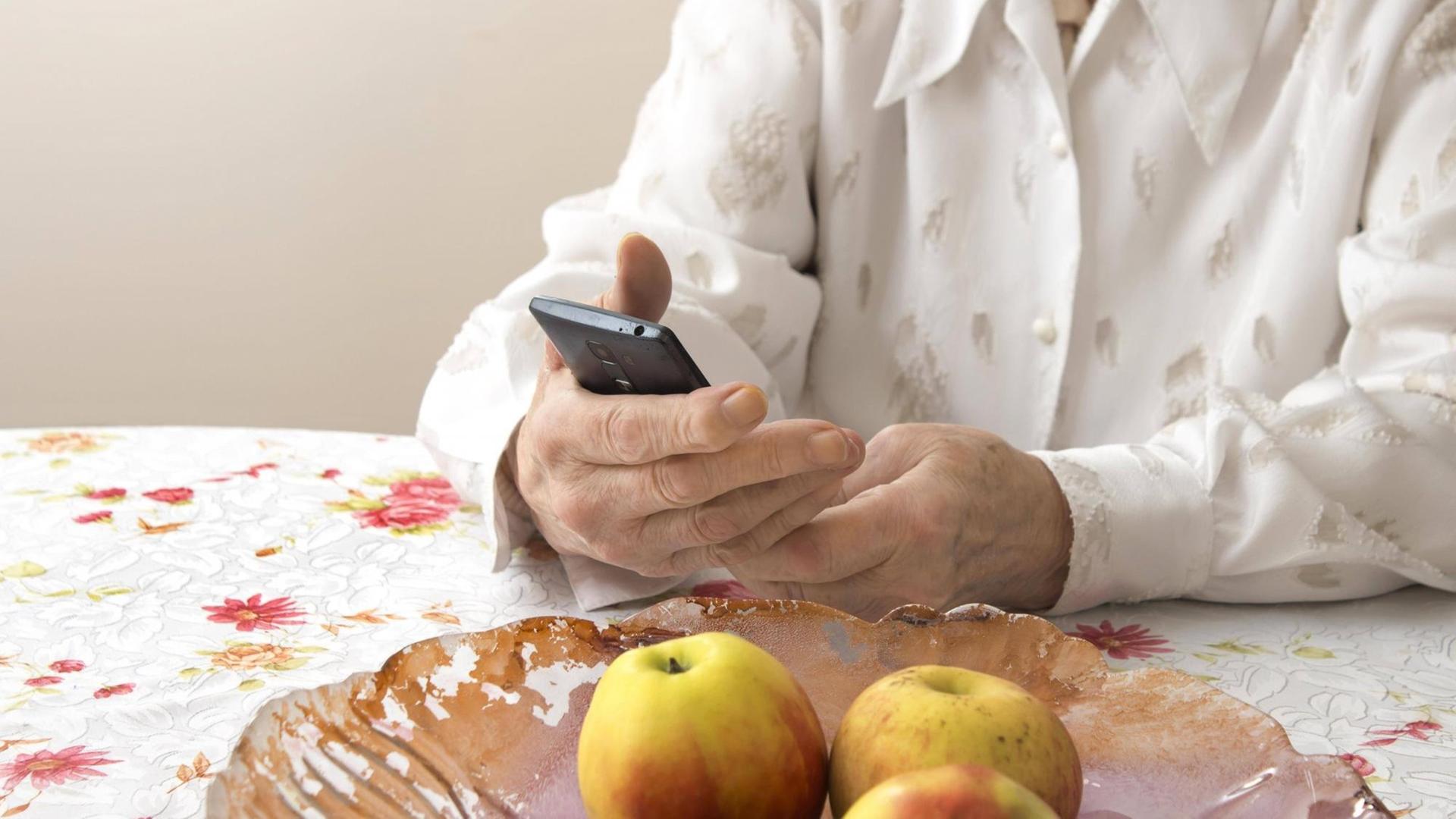 Die Hände einer älteren Frau halten ein Mobiltelefon. (Symbolfoto) Die Hände einer älteren Frau halten ein Mobiltelefon. (Symbolfoto)
