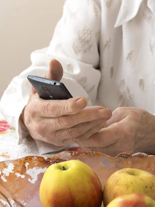 Die Hände einer älteren Frau halten ein Mobiltelefon. (Symbolfoto)
