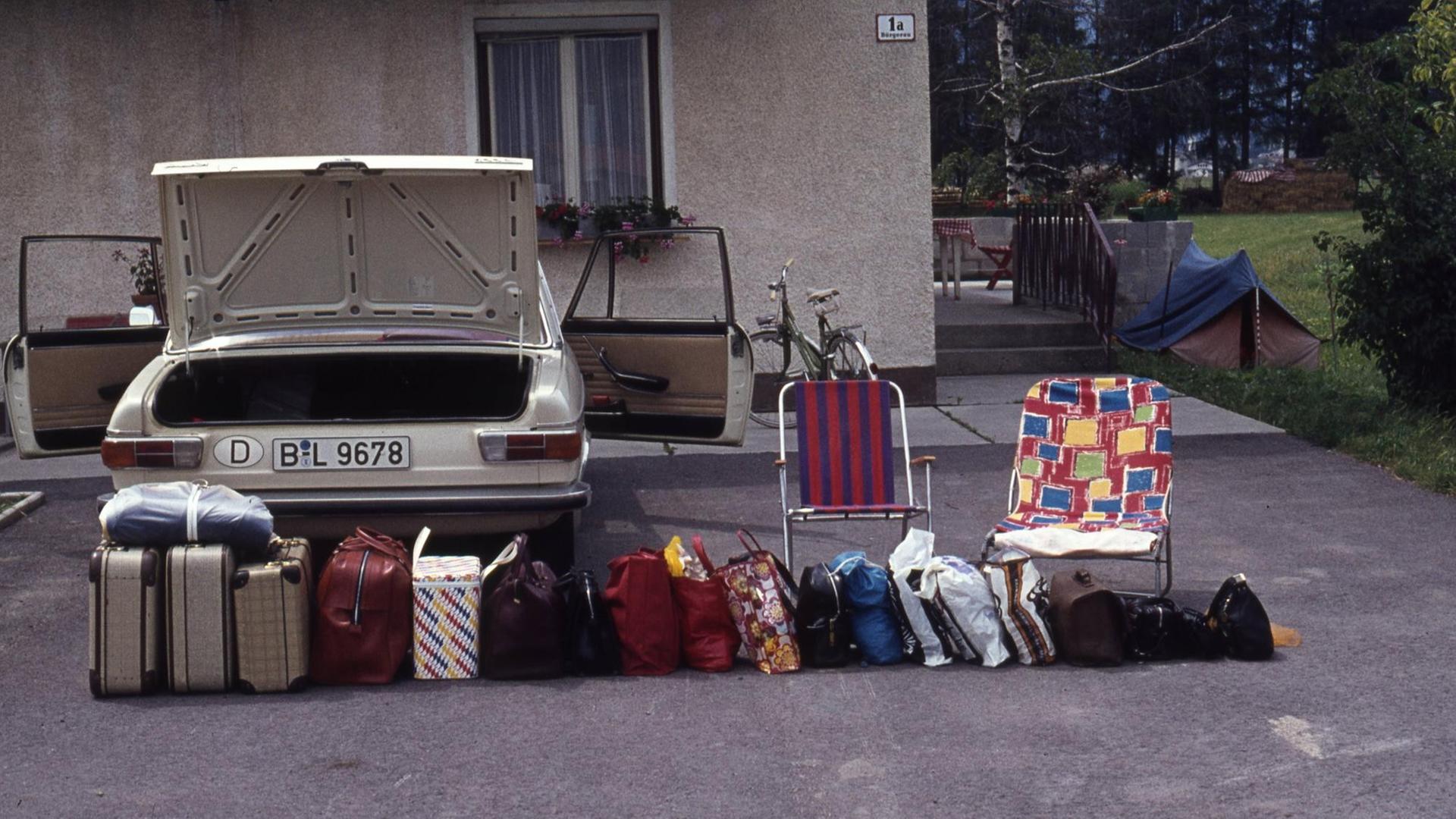In einer Reihe stehen zahlreiche Koffer vor dem Auto. In einer Reihe stehen zahlreiche Koffer vor dem Auto.