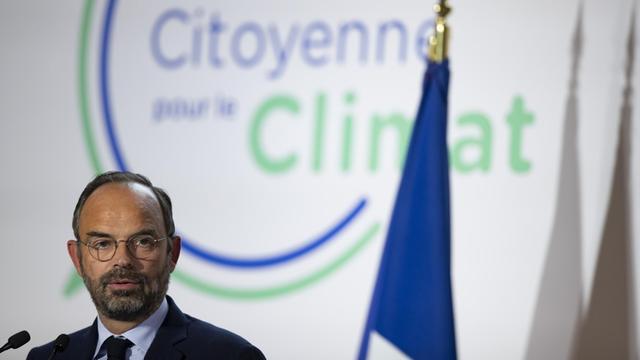 Ministerpräsident Philippe spricht vor einem Logo des Bürgerkonvents zum Klimaschutz.