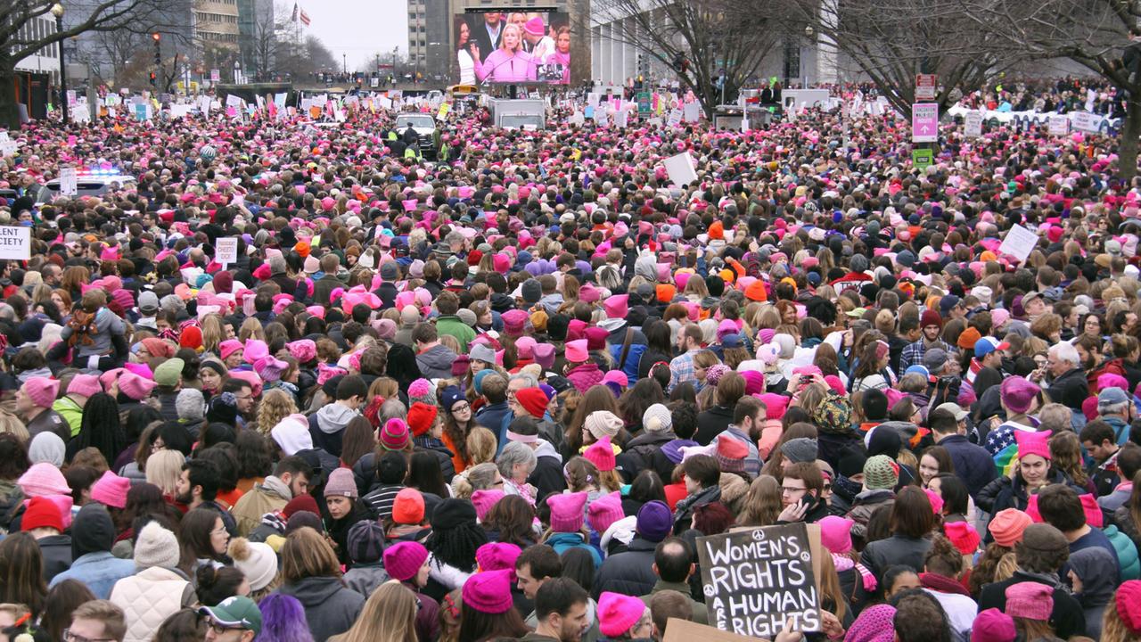 Zahlreiche Menschen demonstrieren und tragen als Zeichen ihres Protest rosa und rote Kopfbedeckung.