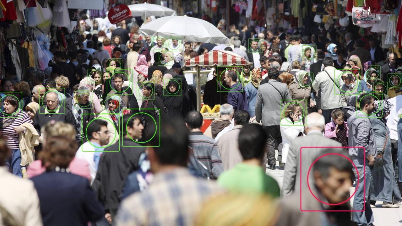 Die Fotomontage zeigt Menschen in der Öffentlichkeit. Bei einigen ist das Gesicht eingekreist, um das Thema Gesichtserkennung zu illustrieren.