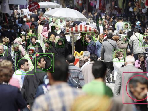 Die Fotomontage zeigt Menschen in der Öffentlichkeit. Bei einigen ist das Gesicht eingekreist, um das Thema Gesichtserkennung zu illustrieren.