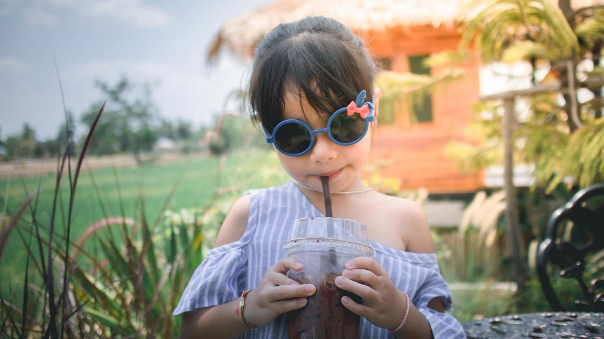 ein junges Mädchen mit Drink und Sonnenbrille auf einem Anwesen ein junges Mädchen mit Drink und Sonnenbrille auf einem Anwesen