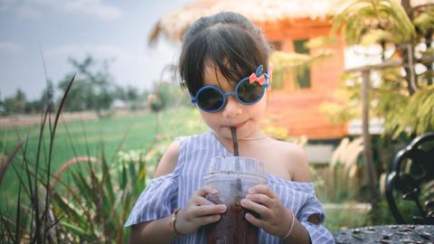 ein junges Mädchen mit Drink und Sonnenbrille auf einem Anwesen