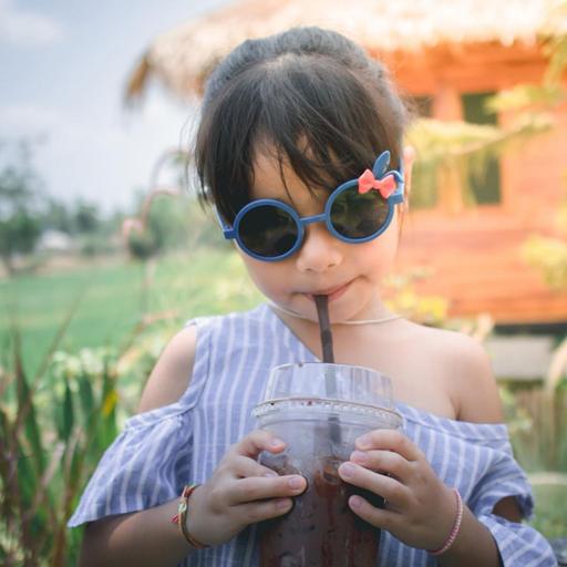 ein junges Mädchen mit Drink und Sonnenbrille auf einem Anwesen