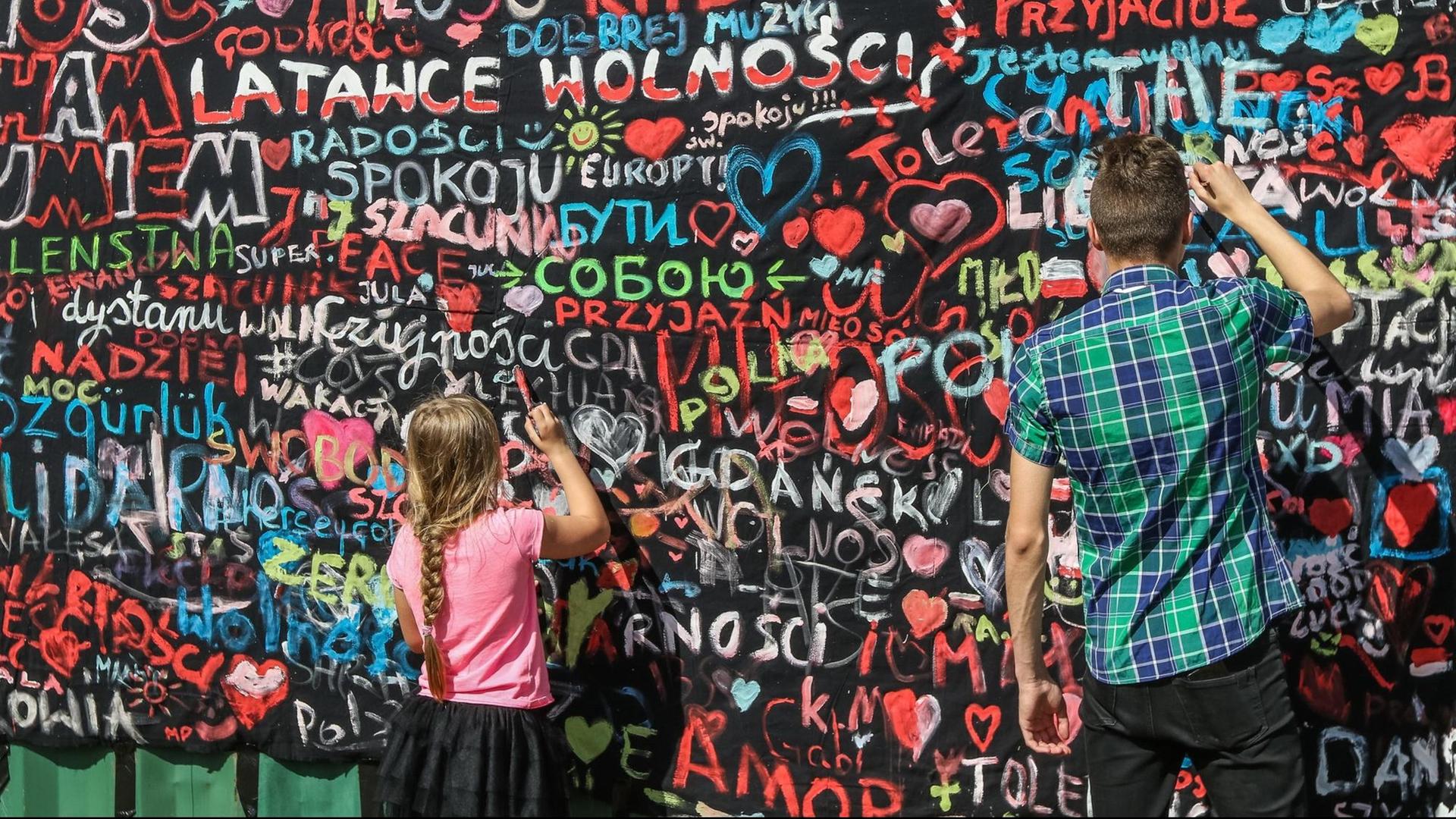 Menschen malen eine Mauer auf der Danziger Werft im Rahmen der "Freiheits- und Solidaritätstage" an. Hier nahm vor 30 Jahren die friedliche Revolution ihren Anfang.