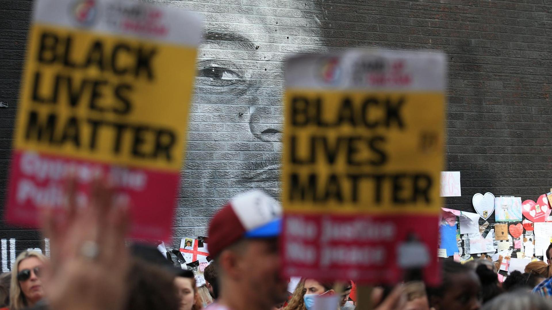 "Black-Lives-Matter"-Plakate werden vor dem Wandbild Marcus Rashfords in die Höhe gehalten. "Black-Lives-Matter"-Plakate werden vor dem Wandbild Marcus Rashfords in die Höhe gehalten.
