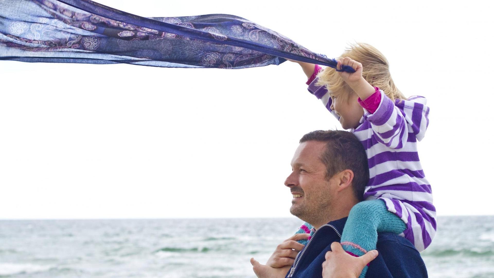 Ein kleines Mädchen und ihr Vater lassen ein Tuch wehen, am Strand von Ringkoebing, Dänemark im Sommer 2014. Ein kleines Mädchen und ihr Vater lassen ein Tuch wehen, am Strand von Ringkoebing, Dänemark im Sommer 2014.