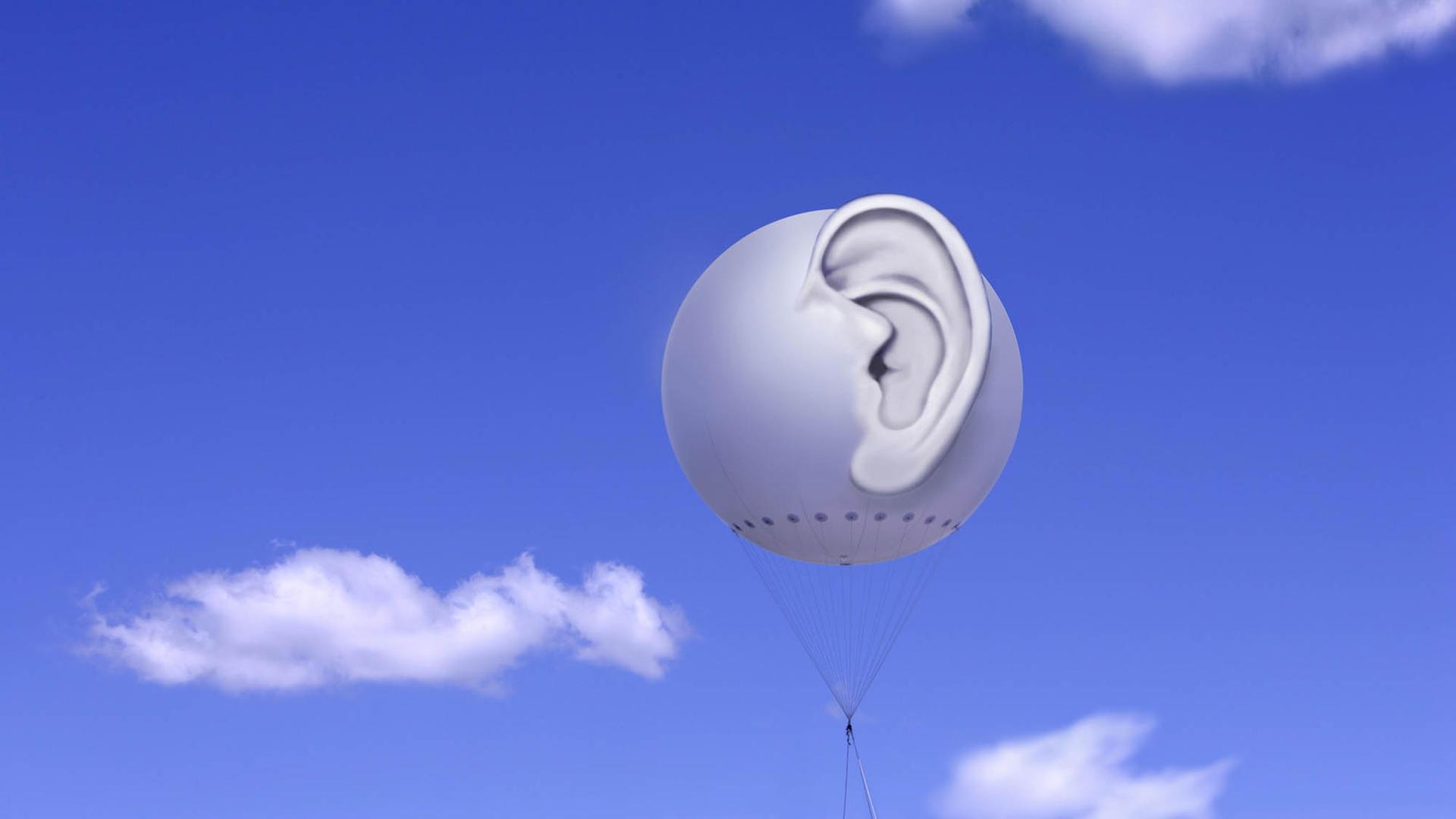 Fesselballon mit dreidimensionalem menschlichem Ohr vor blauem Himmel mit weißen Wolken (Symbolbild) Fesselballon mit dreidimensionalem menschlichem Ohr vor blauem Himmel mit weißen Wolken (Symbolbild)