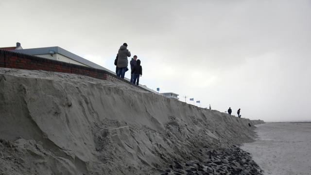 Das Bild zeigt Passanten, die am 29.10.2017 an der Abbruchkante im Mittelfeld des Bade- und Burgenstrandes auf Wangerooge stehen.