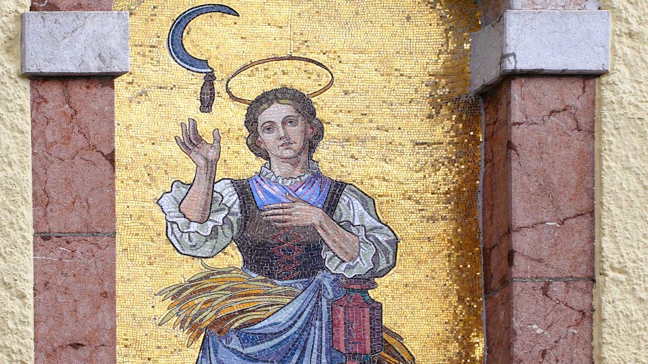 Mosaikbild der Heiligen Notburga mit einer Sichel an der Wallfahrtskirche St. Notburga in Eben am Achensee in Tirol. Mosaikbild der Heiligen Notburga mit einer Sichel an der Wallfahrtskirche St. Notburga in Eben am Achensee in Tirol.