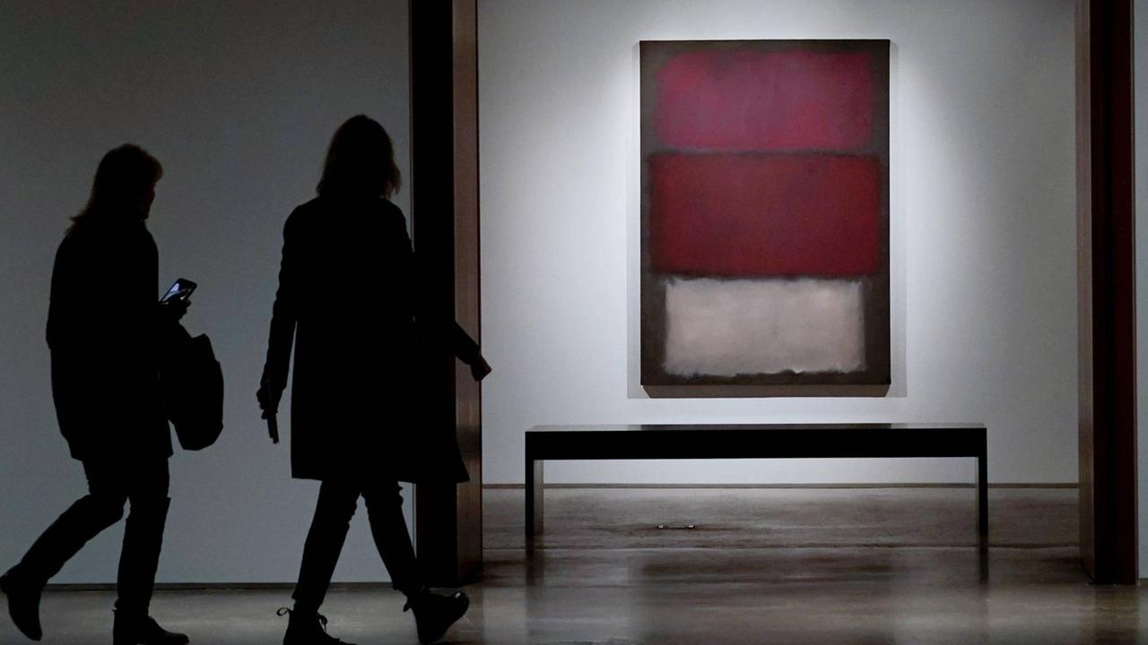 Zwei Besucher gehen in einem Museum auf ein rot gestreiftes Bild zu. Zwei Besucher gehen in einem Museum auf ein rot gestreiftes Bild zu.