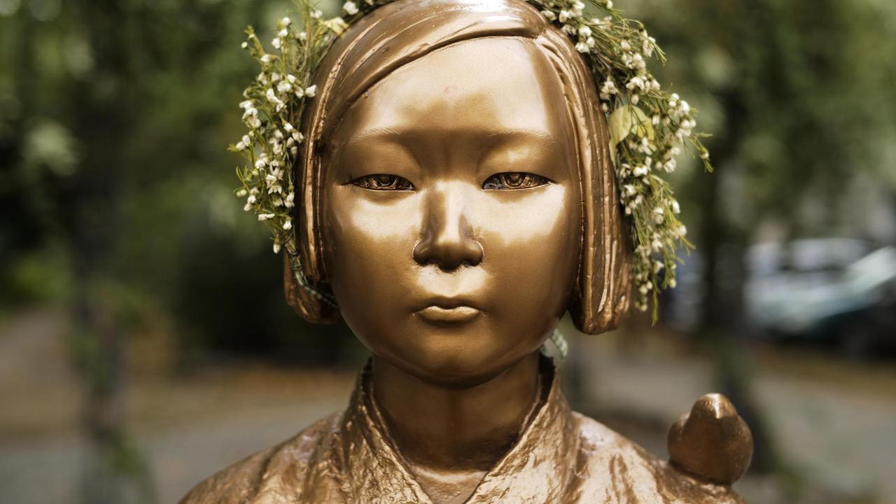 Nahaufnahme der bronzenen Statue eines koreanischen Mädchens mit einem Blumenkranz auf dem Kopf.