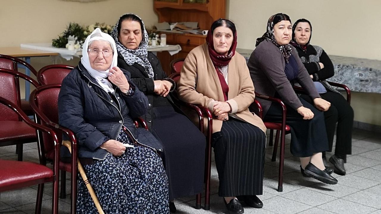 Fünf Jesidinnen bei einer Trauerfeier im jesidischen Gemeindezentrum in Celle. Sie sitzen auf Stühlen und tragen Kopftücher.