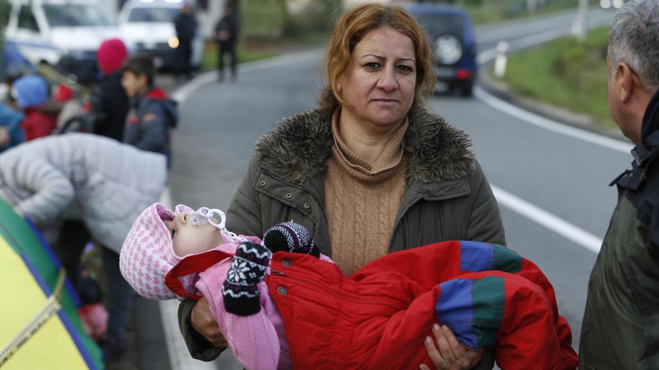 Eine Frau trägt in der Nähe der Grenze von Bosnien zu Kroatien ein schlafendes Kind.