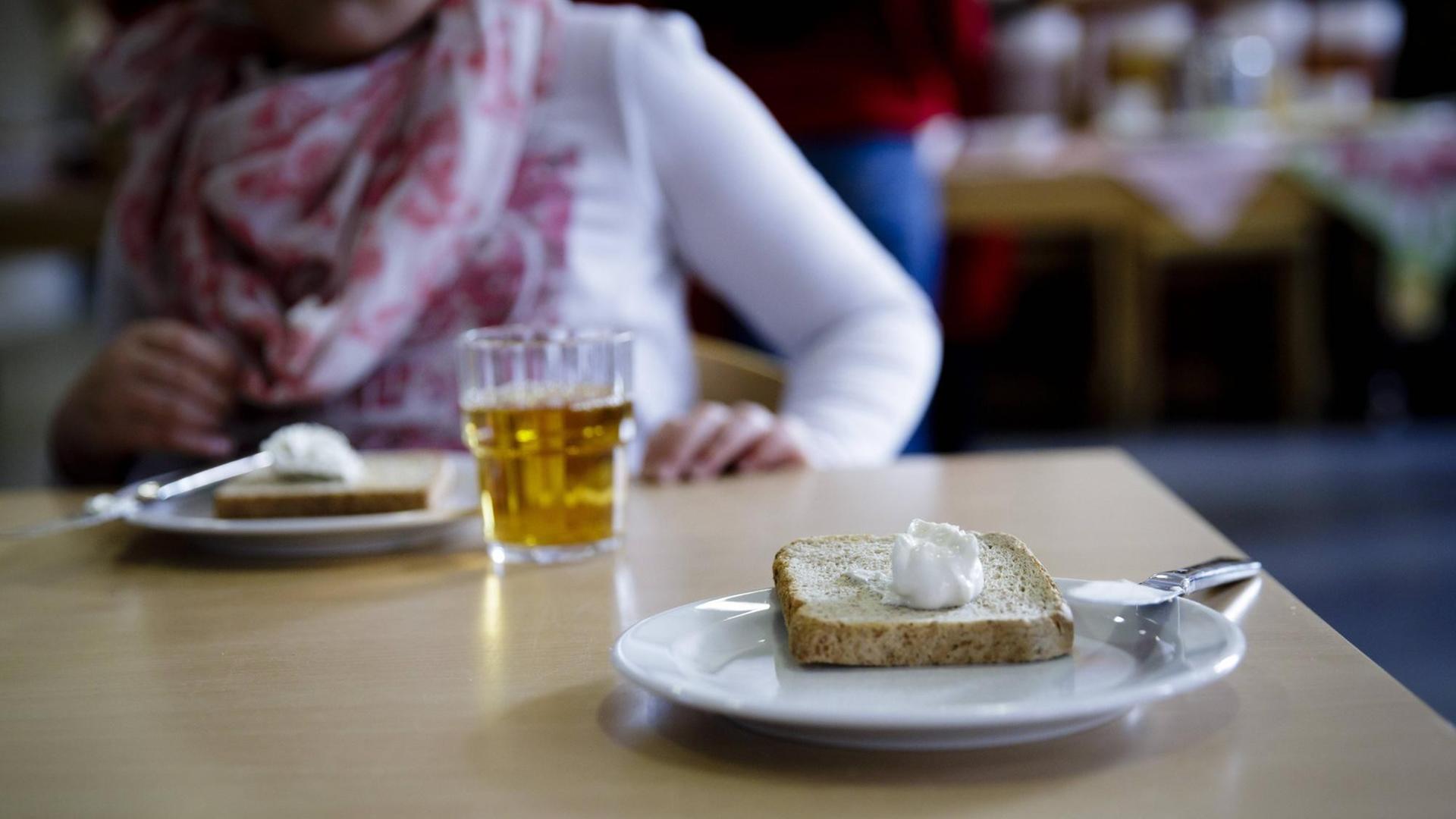 Auf einem Tisch in einem Klassenzimmer stehen zwei Teller mit je einem Butterbrot und ein Glas Apfelsaft. Auf einem Tisch in einem Klassenzimmer stehen zwei Teller mit je einem Butterbrot und ein Glas Apfelsaft.