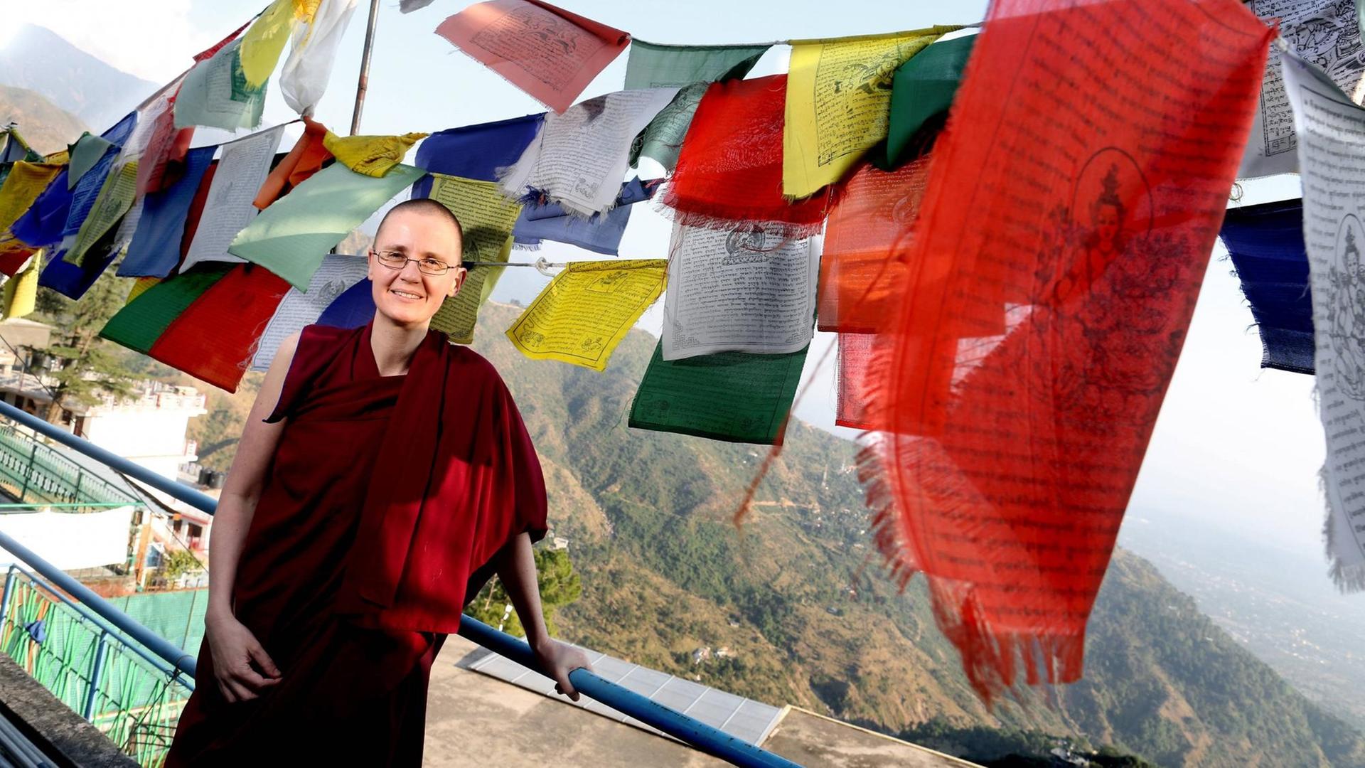 Kelsang Wangmo in Dharamsala, wo sie vor mehr als 20 Jahren den Buddhismus für sich entdeckte. Im Hintergrund die Ausläufer des Himalya Gebirge über ihr tibetische Gebetsfahnen.