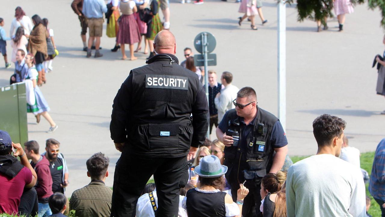 Mitarbeiter einer privaten Sicherheitsfirma kontrollieren auf einer Rasenfläche an der Bavaria