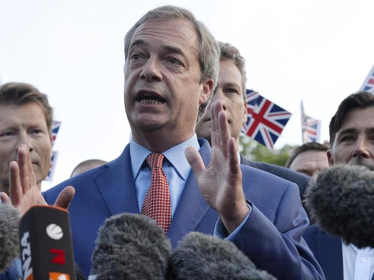 Nigel Farage bei einem Pressestatement umringt von Journalisten und Brexit-Befürwortern mit britischen Flaggen