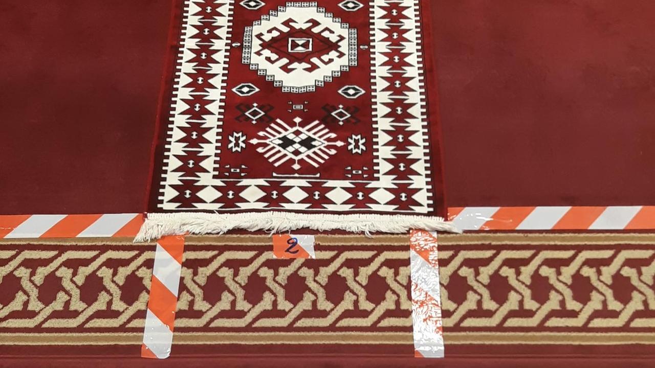 Rot-weiße Klebestreifen markieren auf einem Gebetsteppich, wieviel Abstand die Gläubigen beim Gebet voneinander halten sollen. Rot-weiße Klebestreifen markieren auf einem Gebetsteppich, wieviel Abstand die Gläubigen beim Gebet voneinander halten sollen.