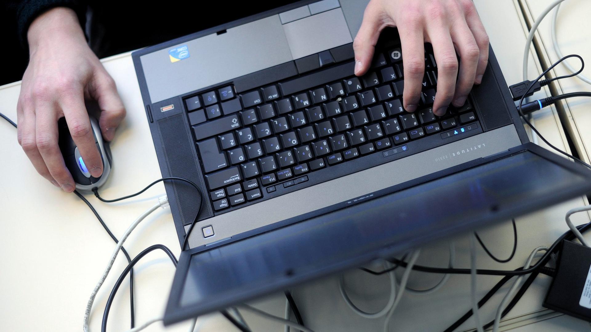 Eine Person bedient einen Laptop mit einer Mouse. Eine Person bedient einen Laptop mit einer Mouse.
