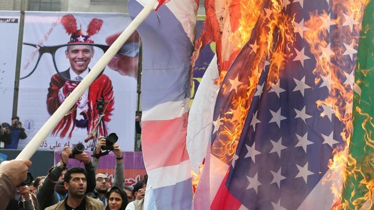 Iraner brennen in Teheran vor der ehemaligen US-Botschaft die Flagge der USA ab. Iraner brennen in Teheran vor der ehemaligen US-Botschaft die Flagge der USA ab.