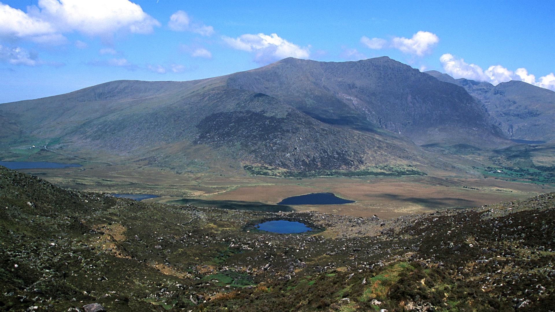 Blick auf die Zufahrt zum Connor Pass auf der Halbinsel Dingle in der Provinz Kerry im Süden Irlands. Im Hintergrund erhebt sich der Brandon Mountain.