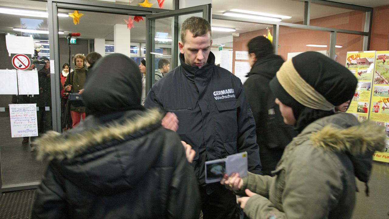 Sicherheitsleute kontrollieren die Schülerausweise von Schülern der Otto-Hahn-Schule in Berlin-Neukölln. Sicherheitsleute kontrollieren die Schülerausweise von Schülern der Otto-Hahn-Schule in Berlin-Neukölln.