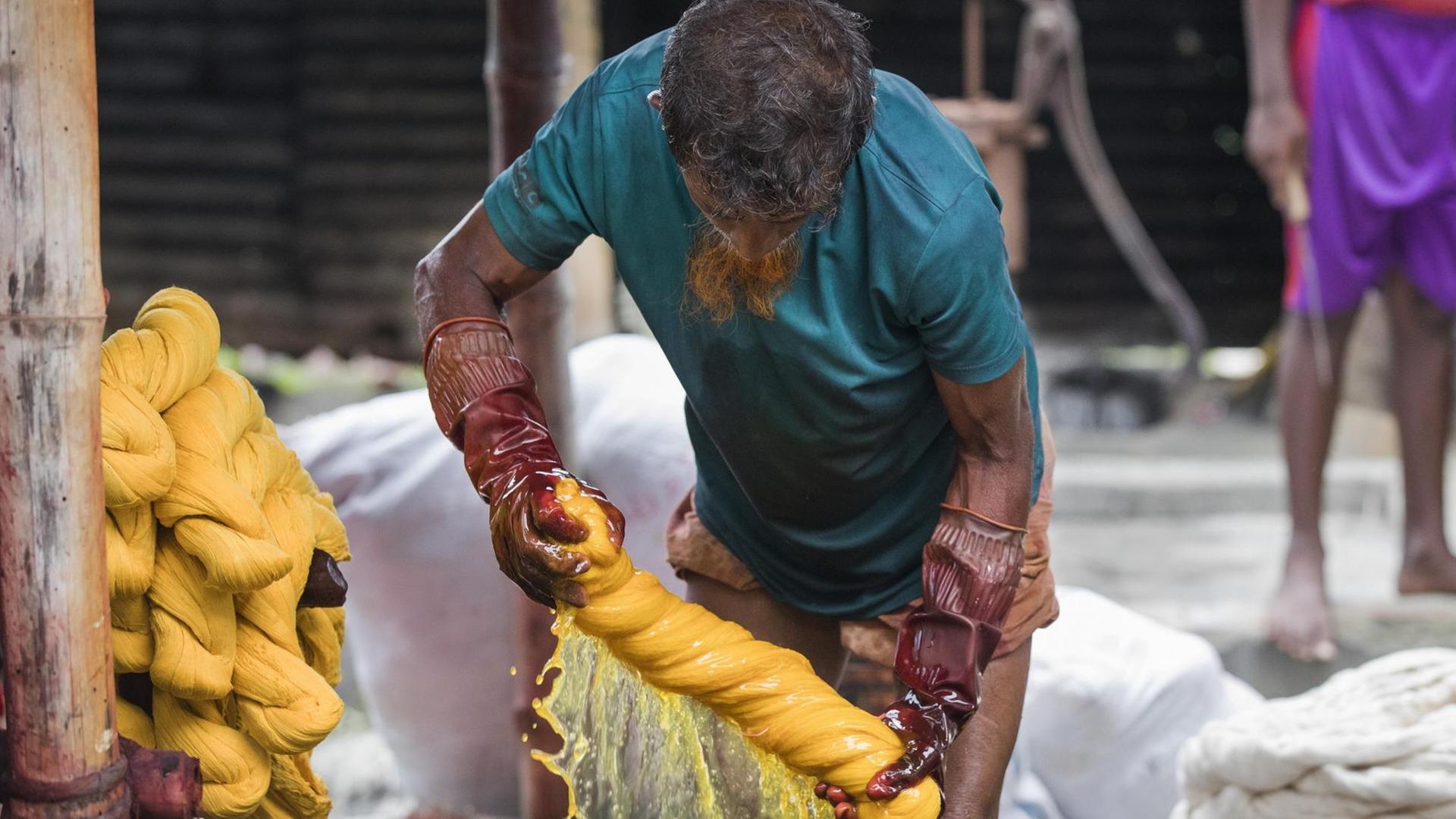 Ein Arbeiter in Bangladesh färbt Kleidung Ein Arbeiter in Bangladesh färbt Kleidung