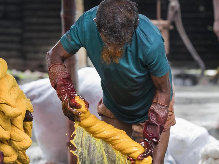 Ein Arbeiter in Bangladesh färbt Kleidung