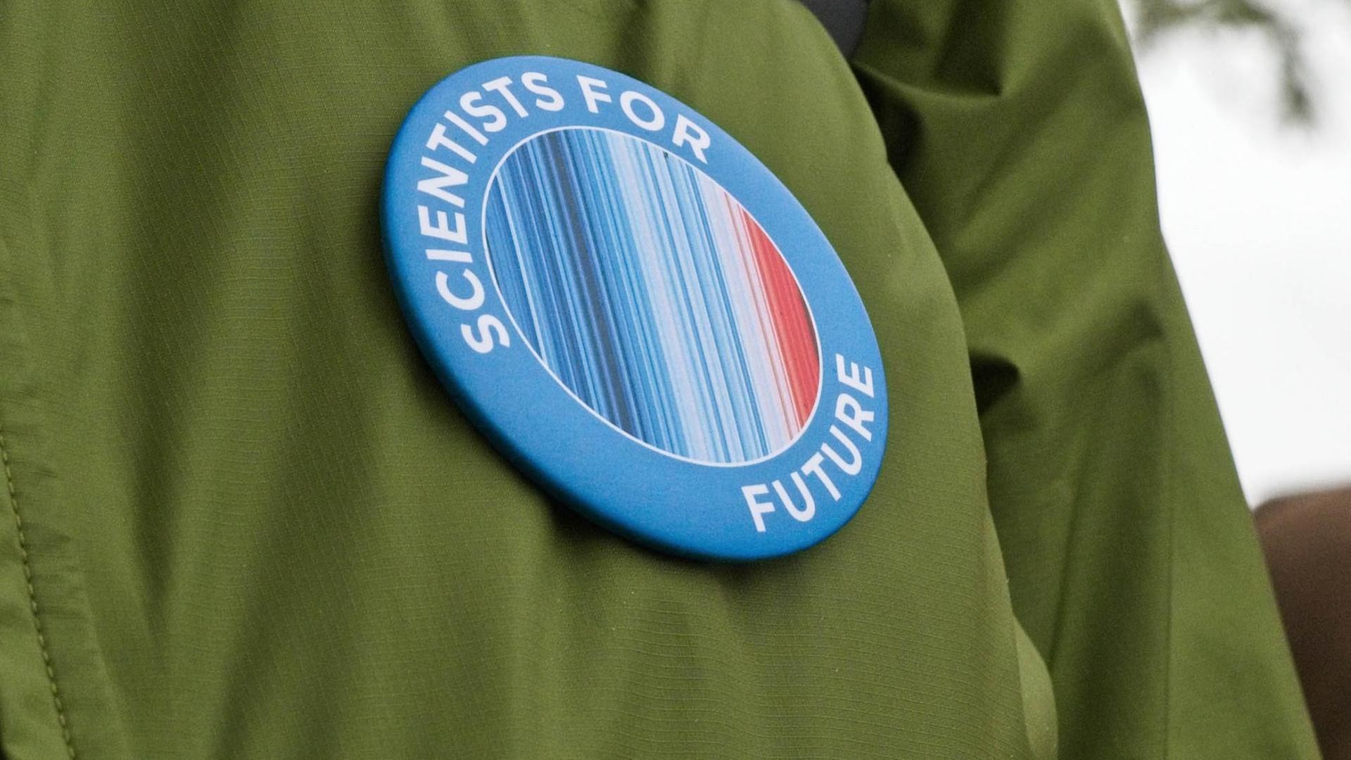 Nahaufnahme einer Anstecknadel mit dem Schriftzug "Scientists for Future". Nahaufnahme einer Anstecknadel mit dem Schriftzug "Scientists for Future".