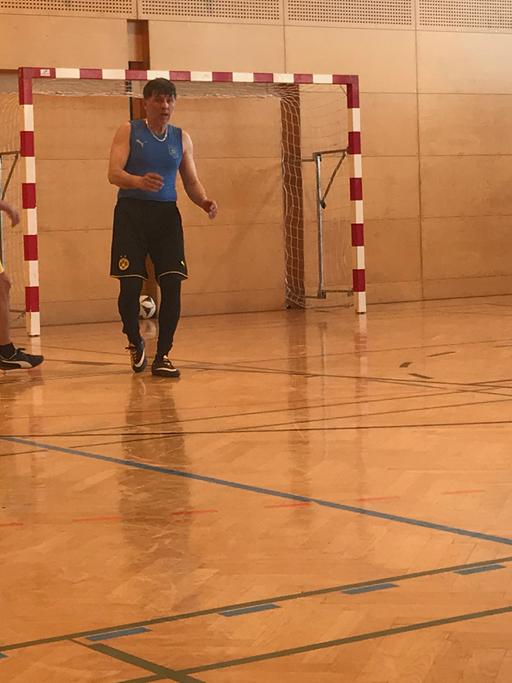 Die Spieler des "FC International" spielen in einer Turnhalle Fußball.
