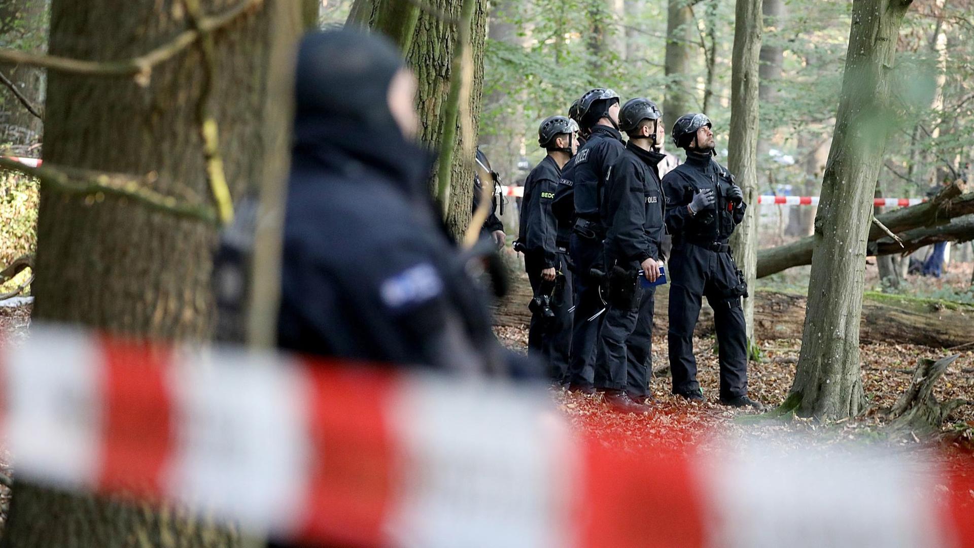 Spezialkräfte der Polizei in schwarzer Montur blicken im Wald zu den Baumhäusern. Spezialkräfte der Polizei in schwarzer Montur blicken im Wald zu den Baumhäusern.