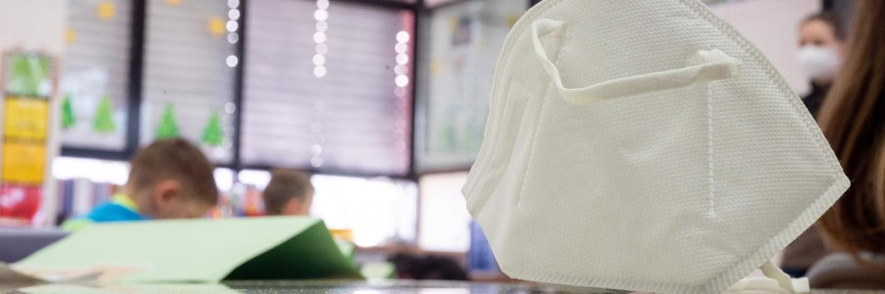 Eine FFP2-Maske liegt in einer ersten Klasse an einer Grundschule auf einem Tisch. Eine FFP2-Maske liegt in einer ersten Klasse an einer Grundschule auf einem Tisch.